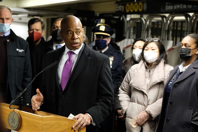 Mayor adams at a lectern inside the Times Square subway station, with other officials, including Rep. Grace Meng and NYPD Commissioner Keechant Sewell, surrounding him